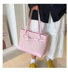 Detail of pink woven tote bag with leather straps and decorative metal buckle belt