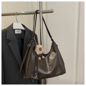 Detail der kaffeebraunen Ledertasche mit funktionalem Seitenreißverschluss und Alpaka-Anhänger