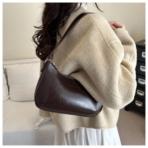 Detailansicht der dunkelbraunen Ölwachs-Leder-Baguette-Tasche, getragen von einem Model