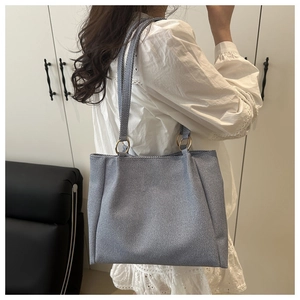 Detail view of large grey tote bag with fabric texture and gold ring strap accents
