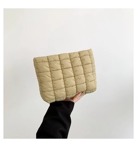 Detail der khakifarbenen gesteppten Puffer-Clutch mit weicher Textur und Handtrage-Stil