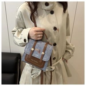 Blue denim crossbody bag with brown leather trim and cat illustration on windbreaker model