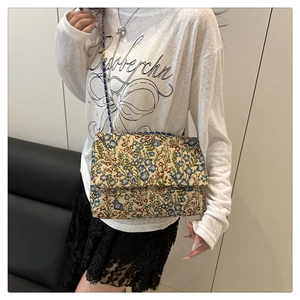Nahaufnahme der Blumenstickerei und Goldkette an der Vintage-Quadrat-Handtasche