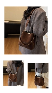 Detail view of dark brown suede bucket bag with adjustable wide strap and metallic trim