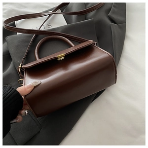 Detail of vintage brown leather handbag featuring a gold buckle on a grey blazer