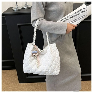 Close-up of white quilted tote bag with woven rope handle and StellaLou rabbit charm