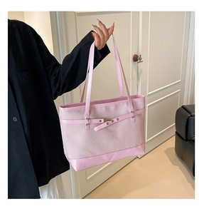 Detail of pink woven tote bag showing texture and leather strap with metal studs