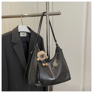 Detailansicht der schwarzen Ledertasche mit Alpaka-Anhänger und weißem Textaufdruck