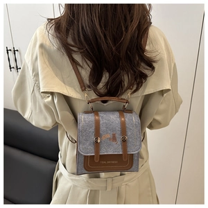 Detail view of the gray felt and brown leather patchwork design on a stylish small backpack