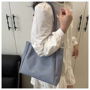 Close-up of blue denim tote bag shoulder strap and premium fabric texture on model