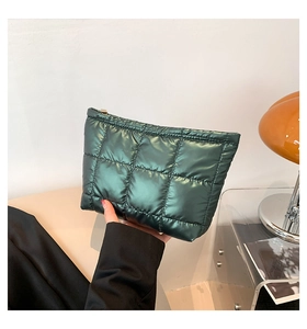 Vue rapprochée d'une pochette matelassée vert foncé avec fermeture éclair et texture soyeuse