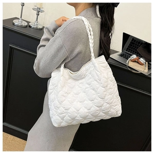 Detailed view of white quilted shoulder bag with woven strap and heart pattern