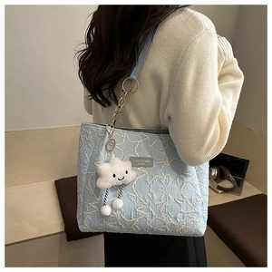 Détail du cabas bleu matelassé avec broderie étoilée et breloque nuage en peluche