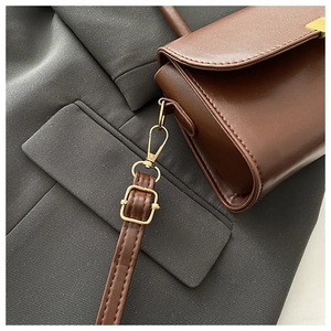 Detail of vintage brown leather bag showing gold buckle and adjustable strap hardware