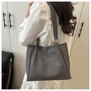 Detail of dark grey tote bag showing twill texture and gold metal ring connection