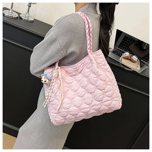 Detail view of pink heart quilted puffer tote bag with woven strap and plush charm