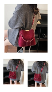 Detail of burgundy suede bucket bag featuring golden metal trim and striped strap