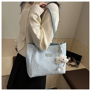 Détail du sac cabas brodé bleu clair avec motifs d'étoiles et bandoulière dorée