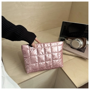 Détail d'un sac à main matelassé rose avec fermeture éclair noire sur un bureau