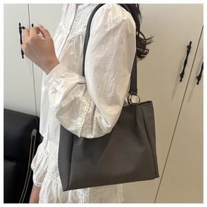 Detail of dark grey textured tote bag featuring a minimalist gold ring buckle on the side