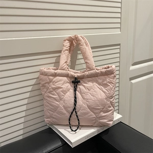 Pink heart quilted tote bag with black drawstring closure on leather chair