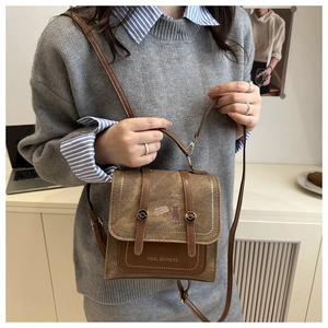 Detail of brown canvas crossbody bag with cat illustration and metallic flip lock