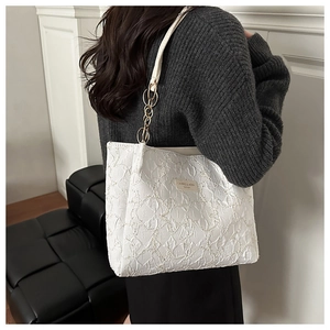 Gros plan du sac cabas blanc avec texture plissée et détail de chaîne dorée