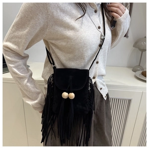 Détail d'un sac bandoulière en suédine noire avec franges et perles porté par un mannequin