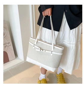 Detail view of contrast stitching and beige woven texture on minimalist tote bag