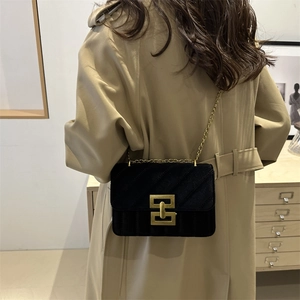 Quilted black velvet crossbody bag with golden chain strap worn over a khaki trench coat