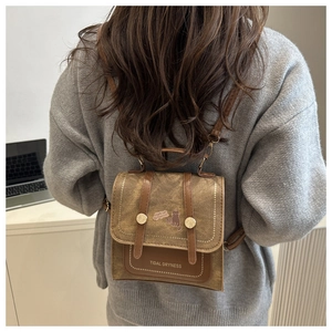 Detail of a brown preppy style mini backpack with cat illustration and flap closure