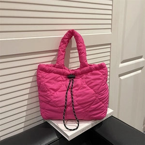 Quilted bright pink tote bag with heart embroidery and drawstring closure on book