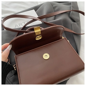 Detail of dark brown leather crossbody bag showing magnetic closure and interior opening