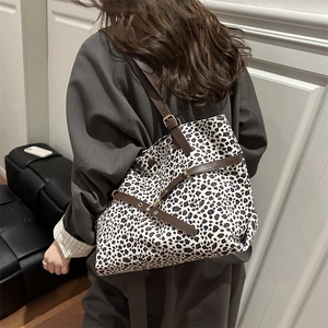 Grand sac cabas léopard avec lanières en cuir porté par un mannequin en manteau gris