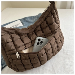 Détail d'un sac cabas matelassé marron foncé avec un smartphone dans la poche avant zippée