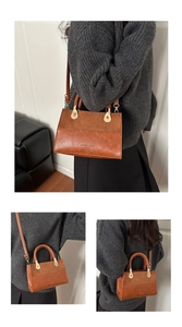 Detail of vintage brown crossbody bag featuring woven handle and textured leather finish