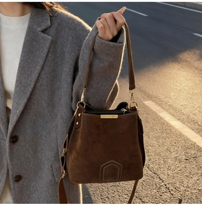 Close-up of deep brown suede bucket bag featuring golden ring hardware and chic stitching