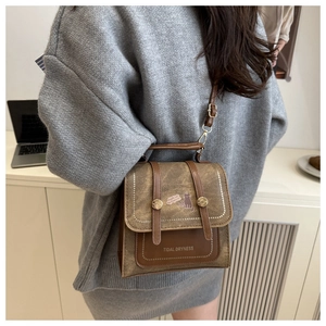 Close-up of brown textured crossbody bag with vintage cat illustration and gold hardware