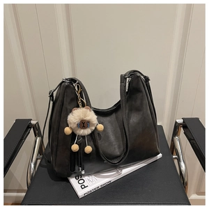 Detail einer schwarzen großen Hobo-Tasche aus mattem PU-Leder mit Plüschbär-Anhänger