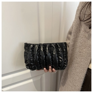 Close-up of black pleated cloud clutch bag featuring glossy leather and accordion folds