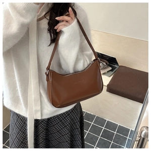 Detail der braunen Leder-Unterachseltasche mit Silberreißverschluss im Büro-Lifestyle