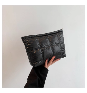 Détail de la pochette en nylon noir matelassé avec une finition brillante et coutures