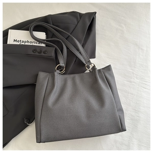 Close-up of deep gray tote bag with canvas texture and gold ring strap fasteners