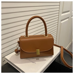 Detail view of a vintage caramel leather handbag with gold metal clasp and top handle