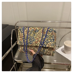 Detailansicht des Vintage-Blumenstickstoffs und des geflochtenen Goldkettenriemens der Tasche