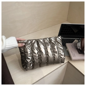 Close-up of metallic bronze quilted cloud clutch bag in a minimalist lifestyle setting