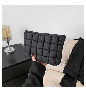 Detailansicht einer schwarzen gesteppten Clutch mit goldenem Dreiecksreißverschluss