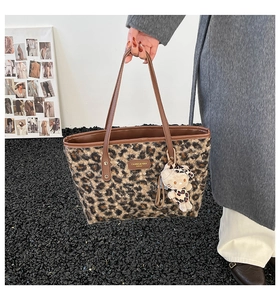 Detail of leopard print tote bag with brown leather handles and brand leather patch