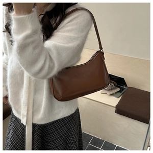 Braune Hobo-Tasche in Halbmondform getragen von einem Modell in minimalistischem Design