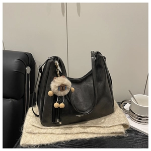 Detail der schwarzen Hobo-Tasche mit Fransenquaste und süßem Plüschbär-Anhänger